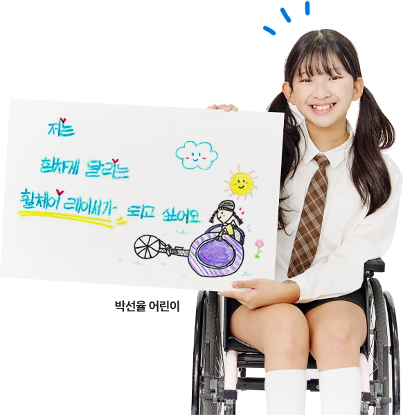 휠체어에 앉은 박선율 어린이가 '저는 힘차게 달리는 휠체어 레이서가 되고 싶어요'라고 쓴 그림을 들고 웃고 있습니다